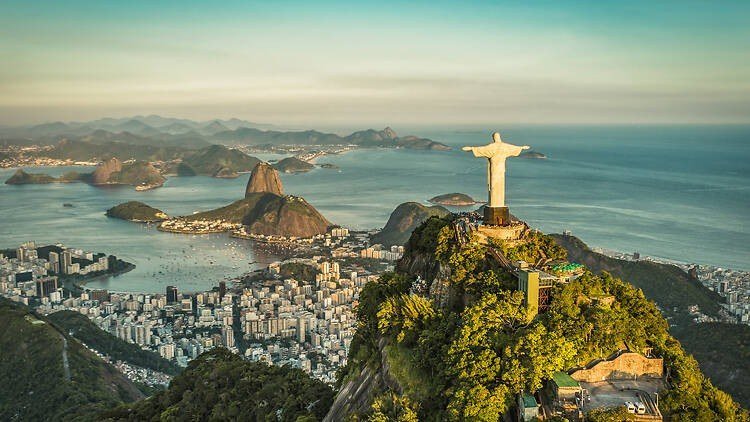 Vista aérea do Rio de Janeiro com o Cristo Redentor no alto do Corcovado, o Pão de Açúcar e a Baía de Guanabara ao fundo