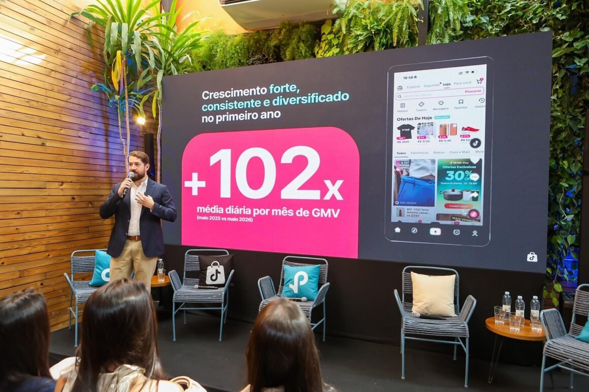 Executivo fala ao microfone diante de painel do TikTok Shop com dados de crescimento e tela do aplicativo, em evento com plateia