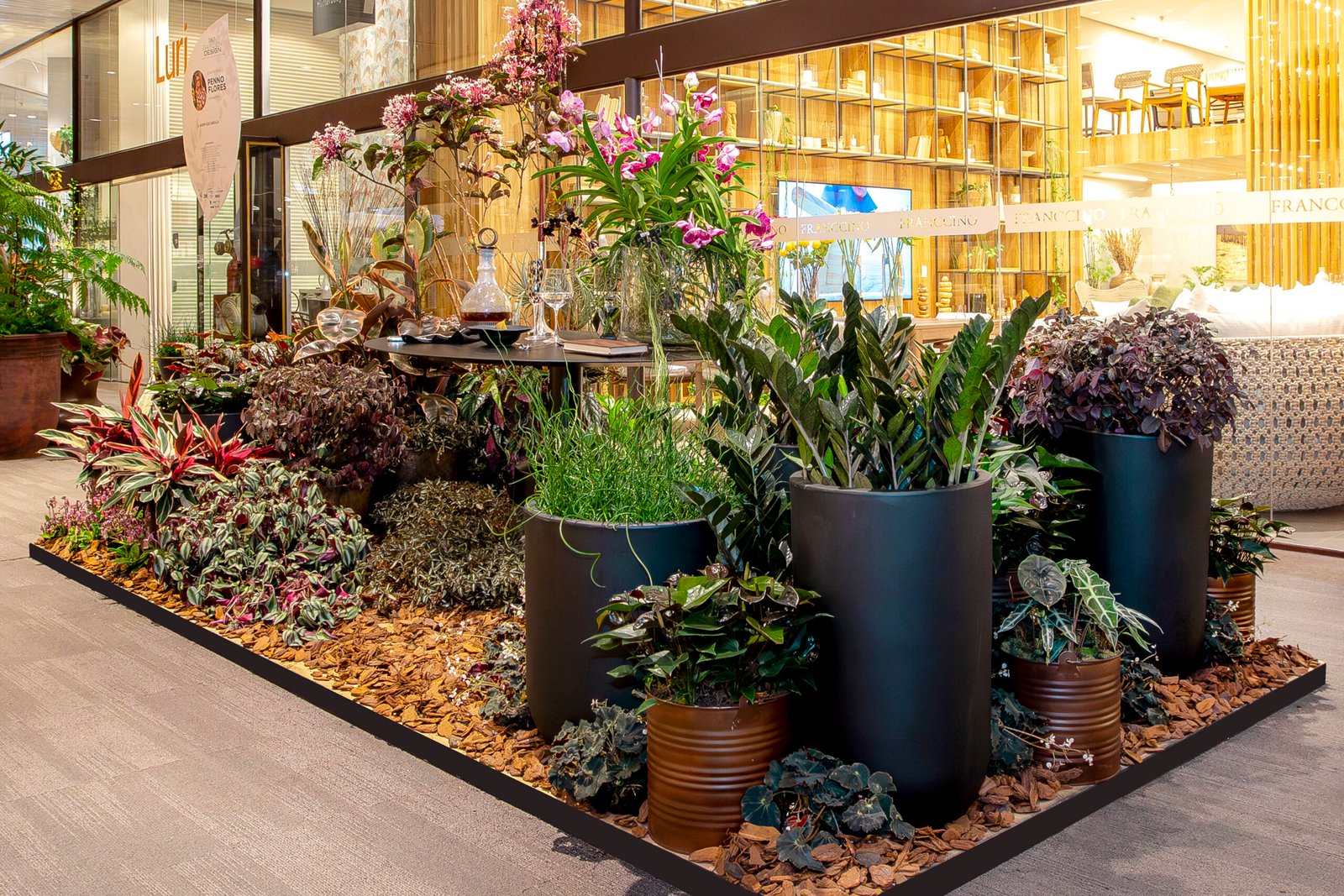 Composição com orquídeas, taças e vasos escuros em um dos estandes da mostra