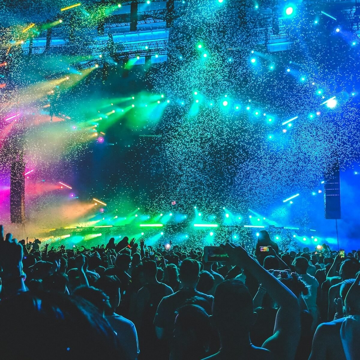 Plateia de show em arena sob luzes coloridas e chuva de confete