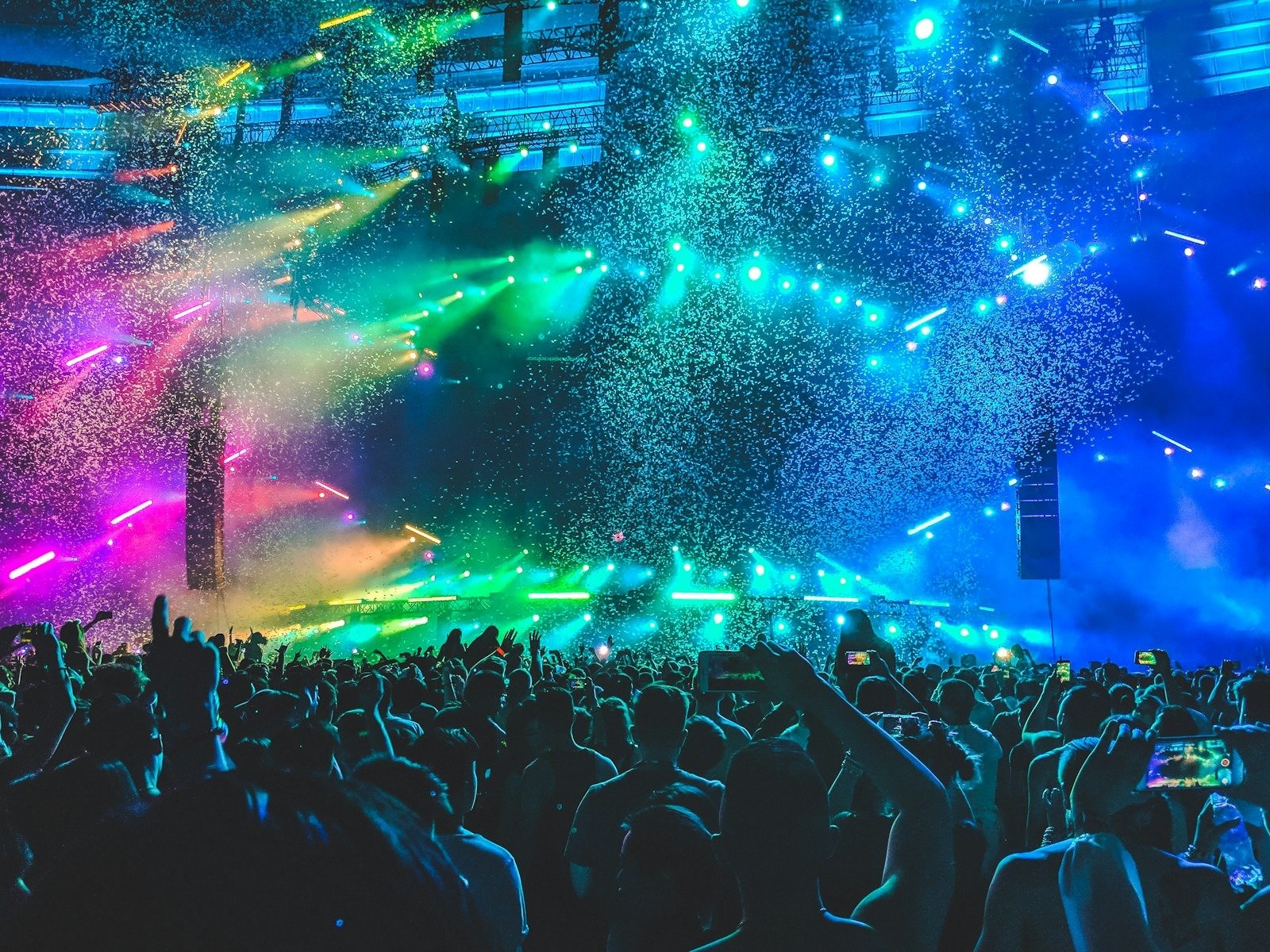 Plateia de show em arena sob luzes coloridas e chuva de confete