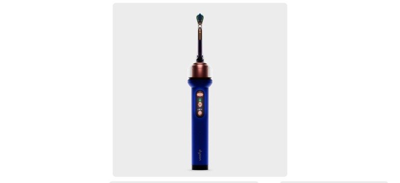 Escova dental Dyson CameraJet azul e cobre, vista de frente sobre fundo cinza-claro.