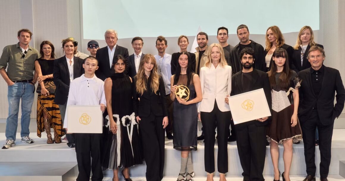 Grupo de jurados e premiados posa no palco da final do Prêmio LVMH, com dois finalistas segurando diplomas