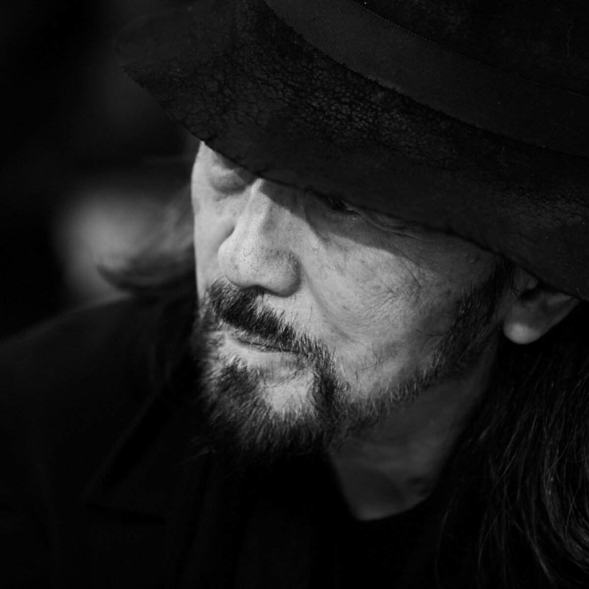 Retrato em preto e branco de Yohji Yamamoto usando chapéu.