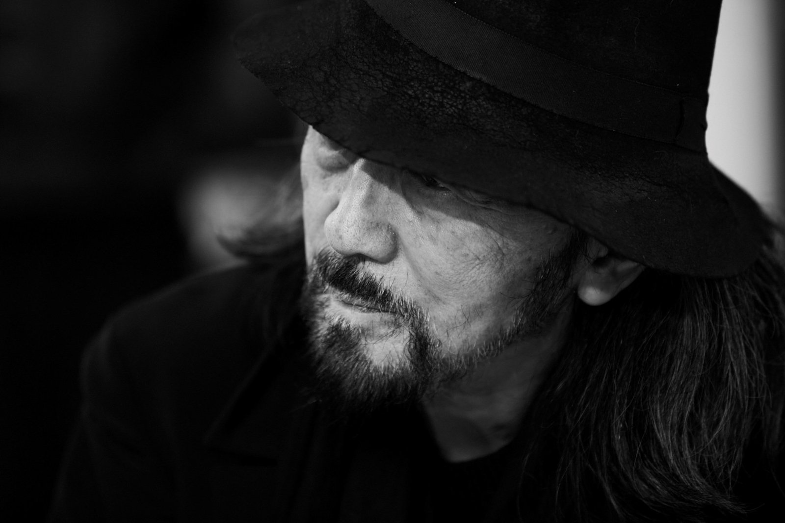 Retrato em preto e branco de Yohji Yamamoto usando chapéu.