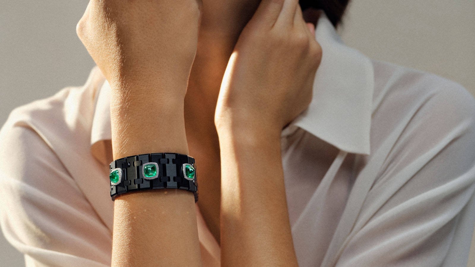 Bracelete da linha Risoud Eclipse, em titânio preto com esmeraldas e diamantes, no pulso de uma modelo.