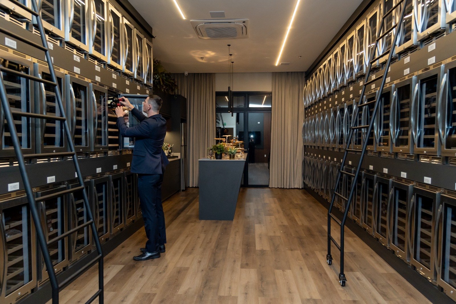 Wine bar do Number One Residence, com adegas climatizadas nas duas paredes e escadas móveis.
