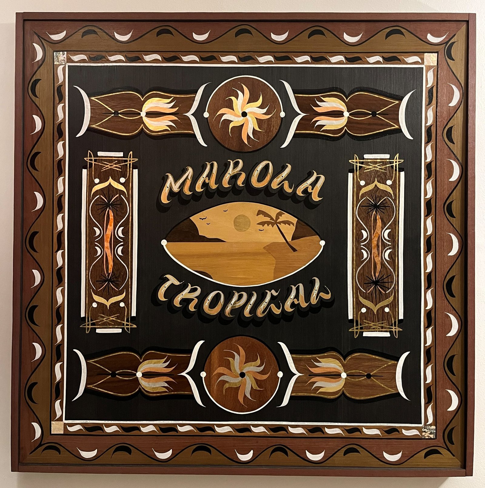 Quadro "Marola Tropical", de Thiago Nevs, em marchetaria de madeiras com moldura ornamentada, letreiro dourado e uma paisagem de praia com coqueiro e sol ao centro