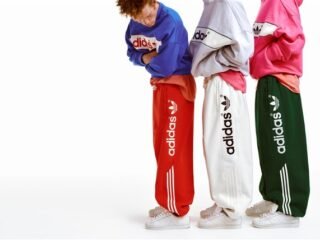 Três modelos com moletons e calças amplas vermelha, branca e verde da linha adiSignature, da Adidas Originals