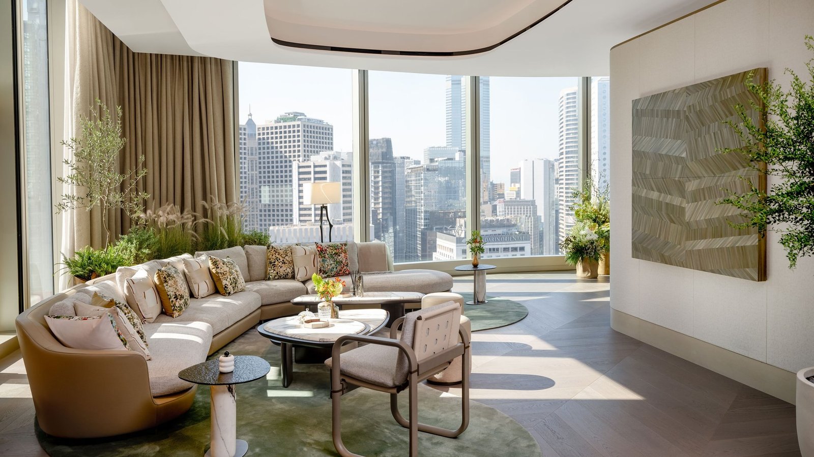 Sala de estar com sofá curvo, mesas de mármore e janelas com vista para os prédios de Hong Kong