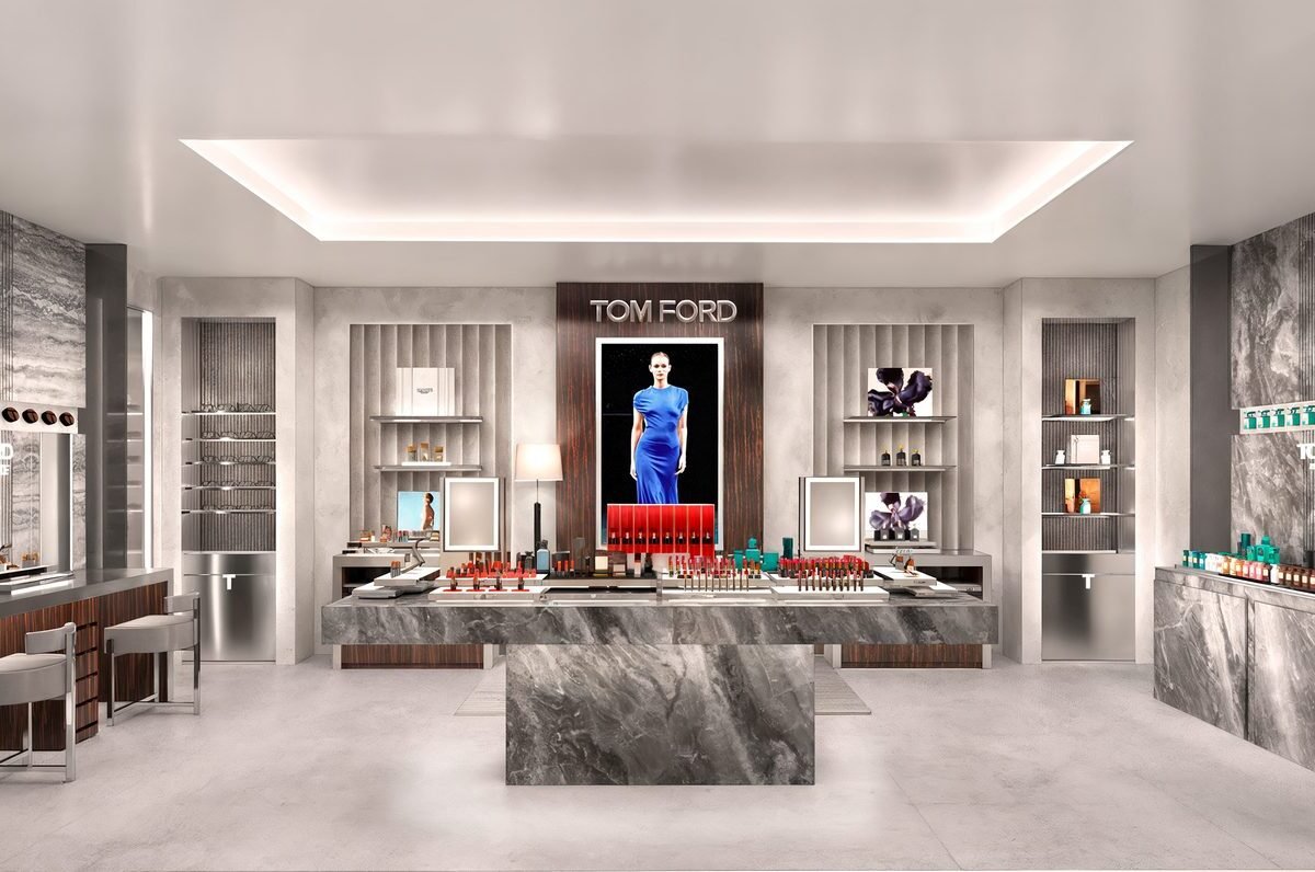 Projeção do interior da flagship Tom Ford Beauty, com balcão central de mármore cinza, painel de madeira escura e displays de maquiagem e fragrâncias