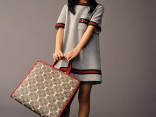 Menina com vestido cinza e bolsa infantil GG da Gucci