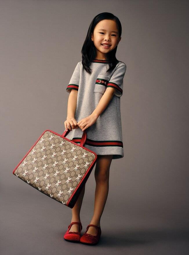 Menina com vestido cinza e bolsa infantil GG da Gucci