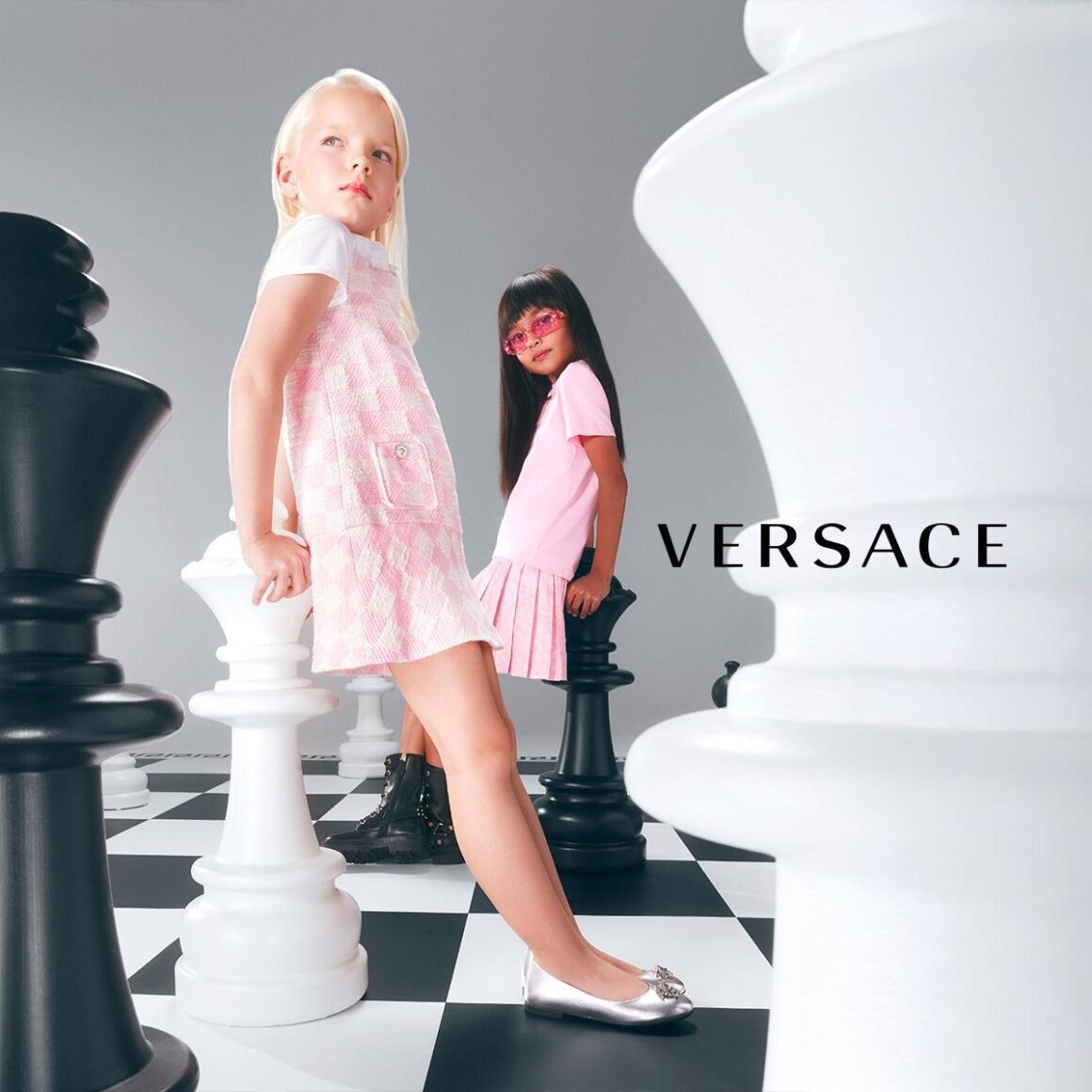 Duas crianças em campanha infantil da Versace, entre peças gigantes de xadrez