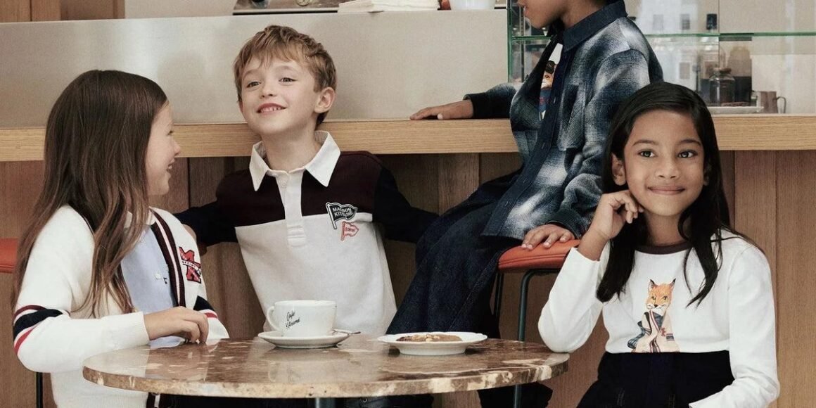 Crianças com peças da coleção Bonpoint x Maison Kitsuné reunidas em torno de uma mesa de mármore no Café Kitsuné