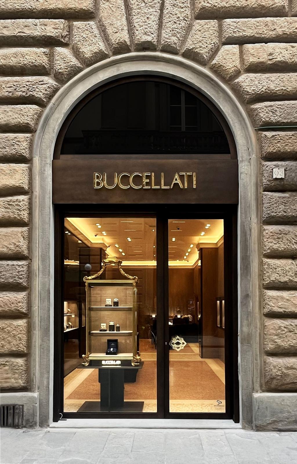 Fachada em arco da boutique Buccellati na Via Tornabuoni, em Florença, com vitrine iluminada.