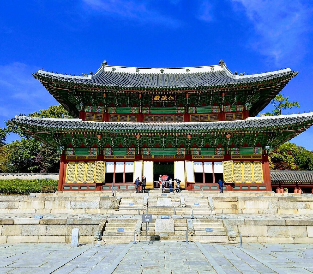Pavilhão Injeongjeon, salão do trono do Palácio Changdeokgung, em Seul, com telhado duplo verde e portas amarelas sob céu azul