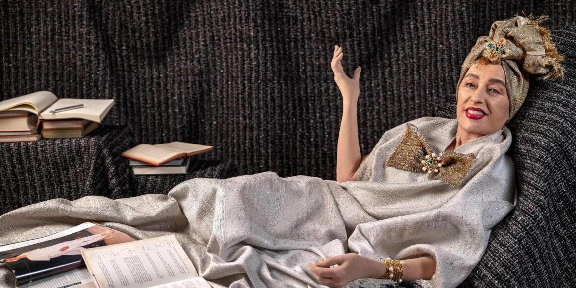 Personagem criada por Cindy Sherman com turbante dourado e tecidos drapeados, recostada em um sofá