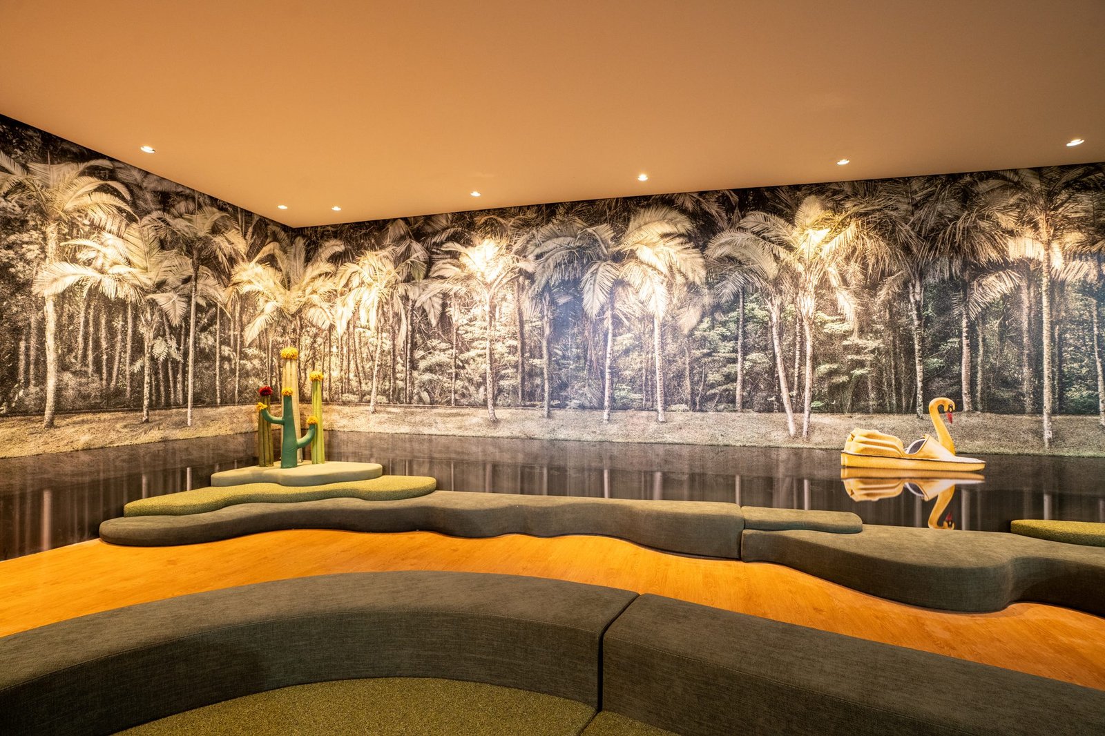 Espaço infantil do Clara Arte com mural de palmeiras, assentos sinuosos e cisne decorativo