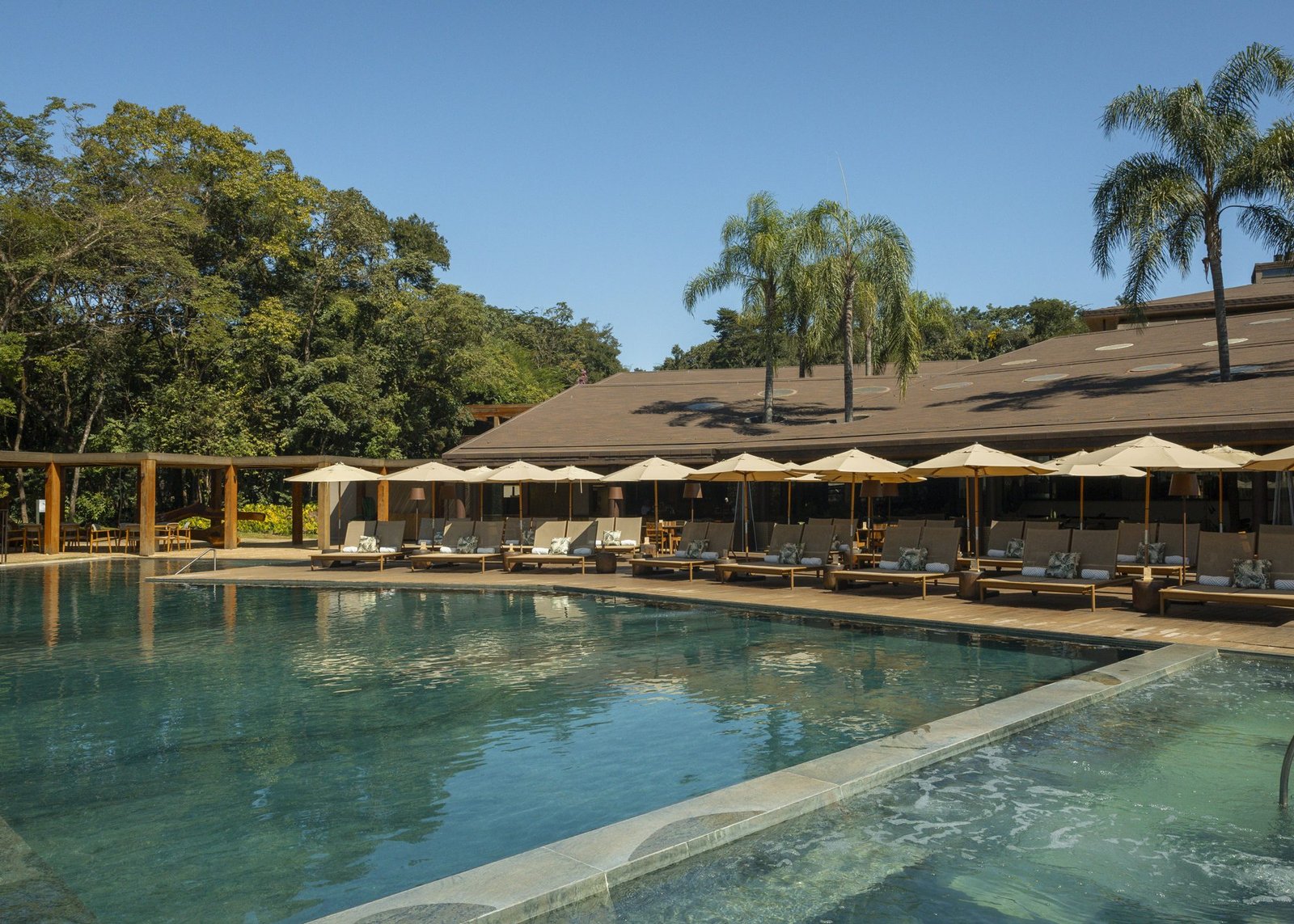 Piscina externa climatizada do Clara Arte com espreguiçadeiras e guarda-sóis