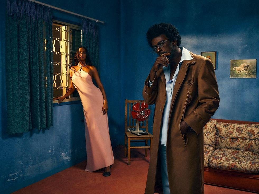 MISCI campaign image with a man in a long brown coat and a woman in a pale pink dress in a blue room