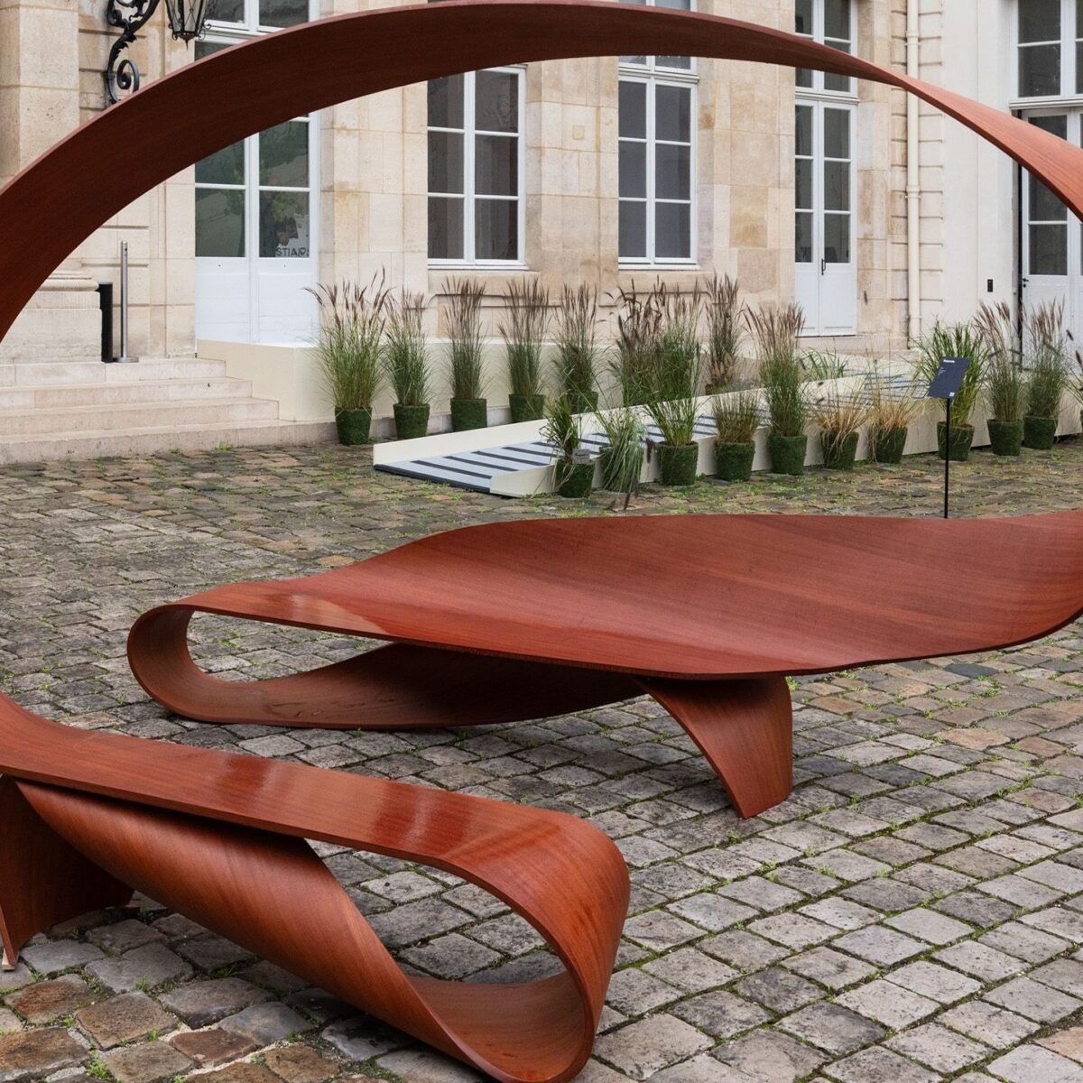 Banco Arabesque, de Pierre Renart, em madeira moabi no jardim do Hôtel de Maisons durante a Design Miami.Paris