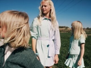 Meninas com vestidos e peças em verde-claro e branco da coleção Versailles Beach, da Dior, em um campo sob céu azul