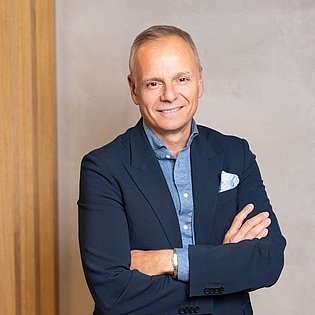 Retrato de Jean-Marc Bellaiche, novo CEO da Douglas, de blazer azul-marinho e braços cruzados