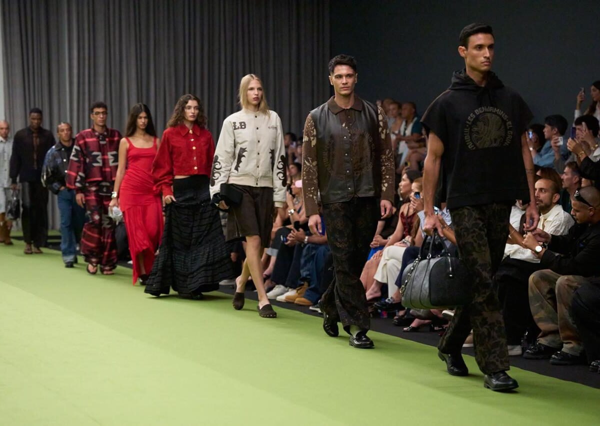 Fila de modelos na passarela verde da Dubai Fashion Week, com plateia ao lado
