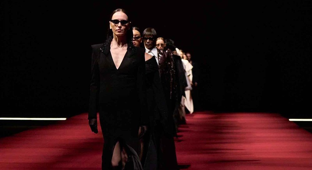 Desfile na Dubai Fashion Week com modelos em looks pretos sobre passarela vermelha