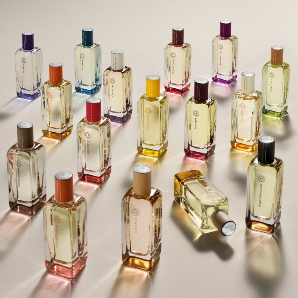 Frascos de perfume Hermessence, da Hermès, com tampas coloridas sobre fundo claro
