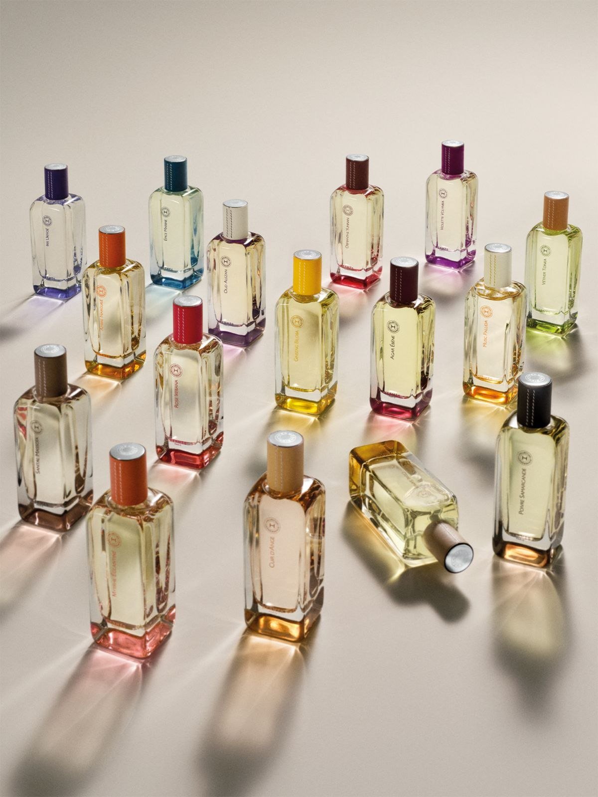 Frascos de perfume Hermessence, da Hermès, com tampas coloridas sobre fundo claro