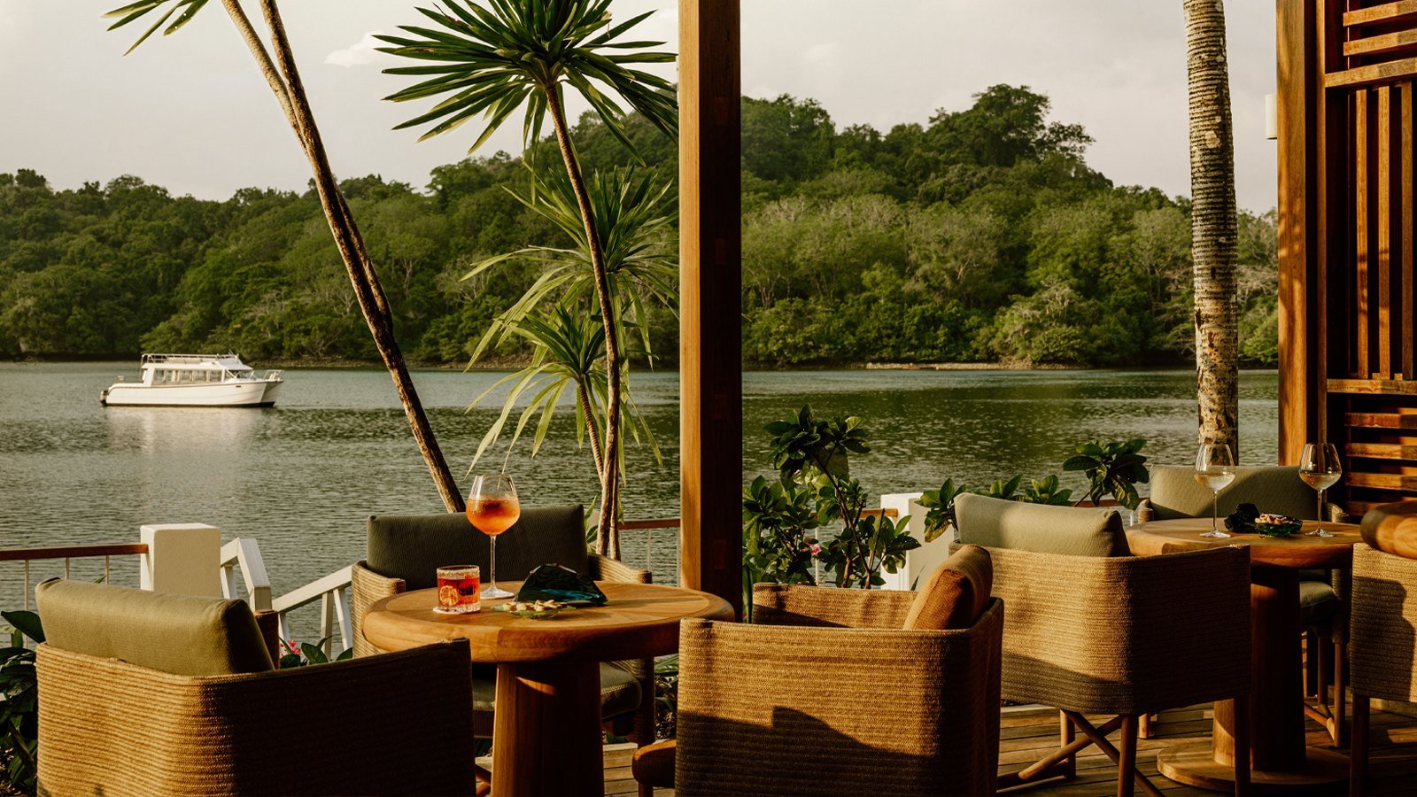 Terraço do M-Dock com poltronas de fibra natural e drinques diante da lagoa de Koror, com barco ao fundo