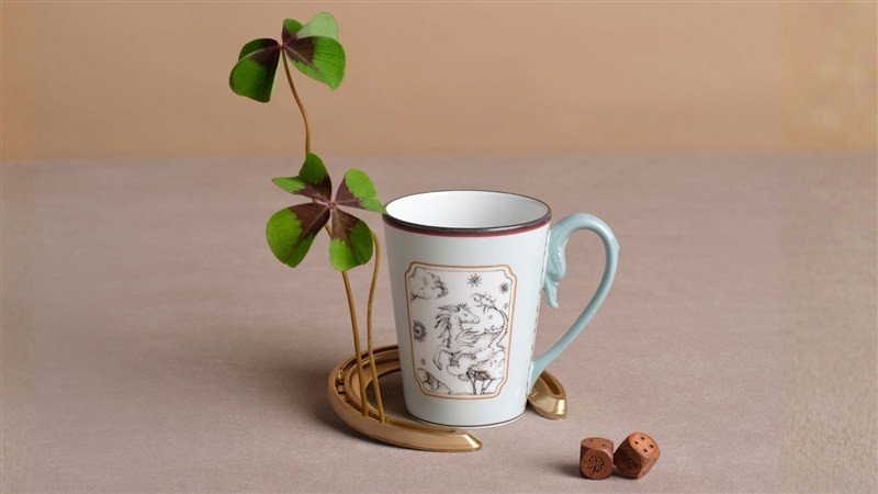 Caneca de porcelana Fortunae com desenho e trevos ao lado.