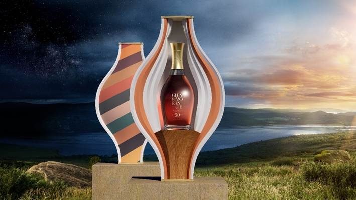 Garrafa do Glenmorangie 50 Years Old dentro de recipiente de porcelana colorido, com paisagem escocesa ao fundo