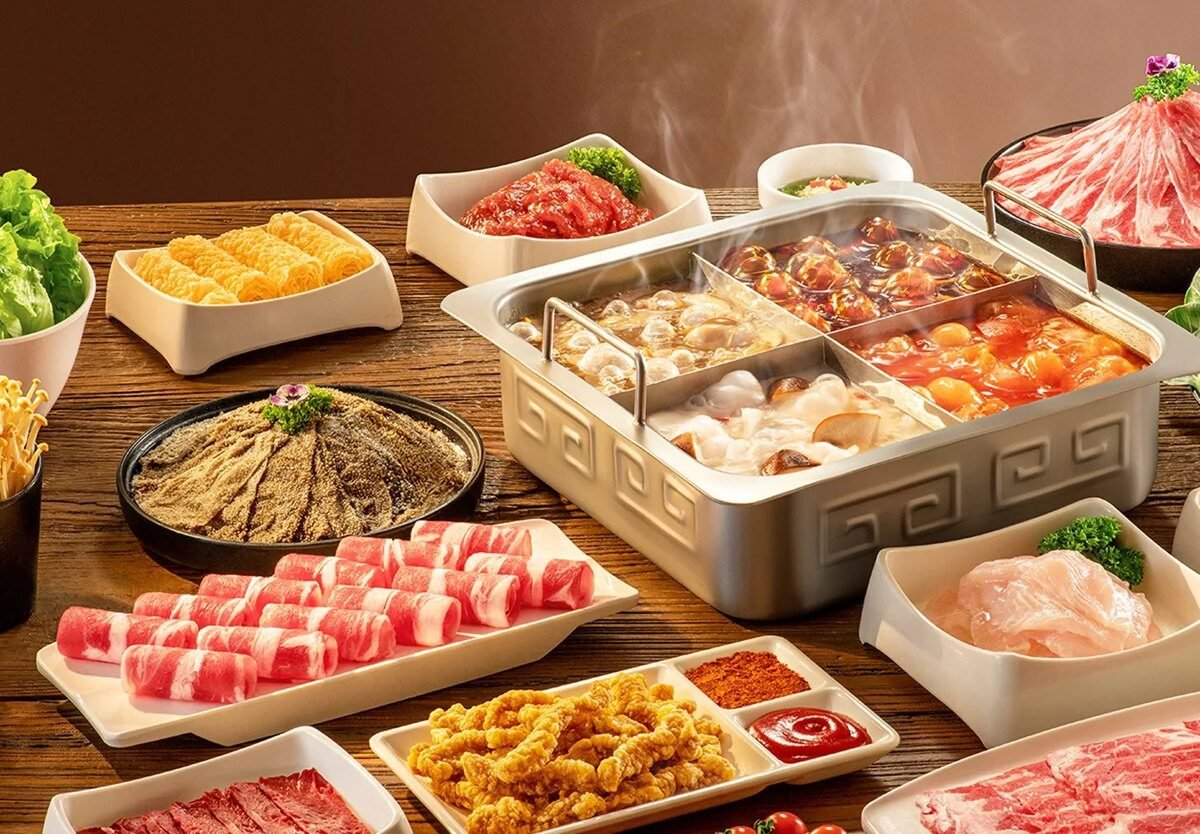 Mesa de hot pot da Haidilao com caldos em panela dividida, carnes fatiadas e vegetais
