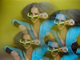 Iara Rennó com óculos de sol verdes em foto de múltipla exposição sobre fundo amarelo