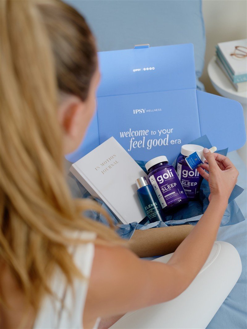 Consumidora observa produtos em uma caixa azul da IPSY Wellness