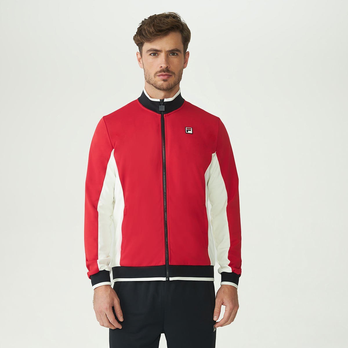 Modelo veste a jaqueta Fila Heritage F-Box vermelha com recortes brancos e gola alta