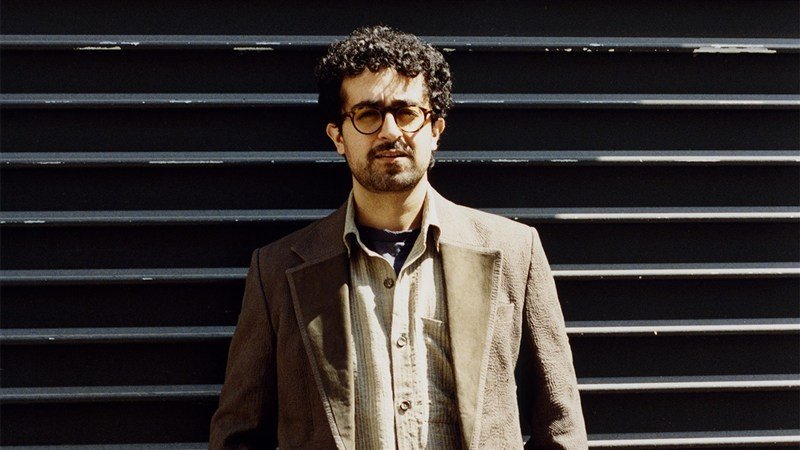 Retrato do designer Kartik Kumra diante de uma parede escura.
