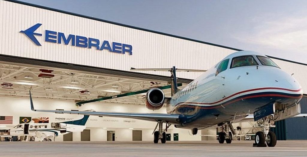 Jato comercial da Embraer diante de hangar da fabricante
