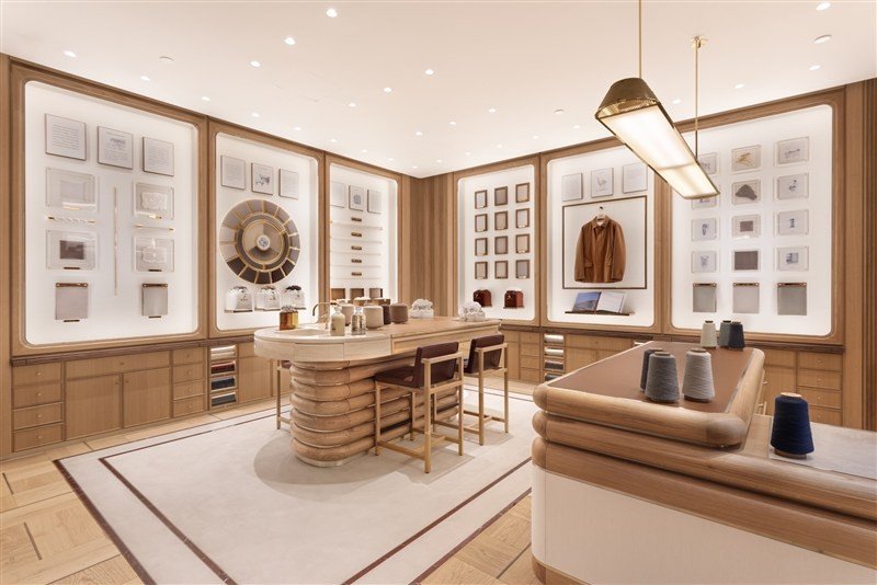 Interior claro do atelier Loro Piana, com bancada, amostras de fibras e peças expostas.