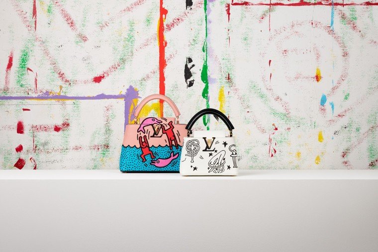 Bolsas Louis Vuitton Artycapucines com desenhos de Keith Haring diante de obra do artista.