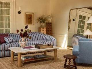 Sala montada no showroom da Lulu and Georgia, com sofá listrado, mesa de centro e objetos de decoração