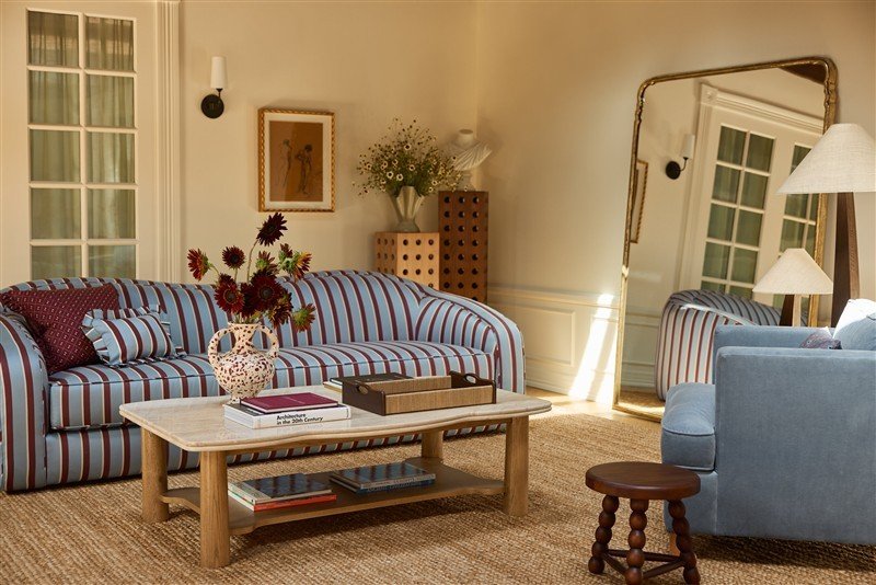 Sala montada no showroom da Lulu and Georgia, com sofá listrado, mesa de centro e objetos de decoração