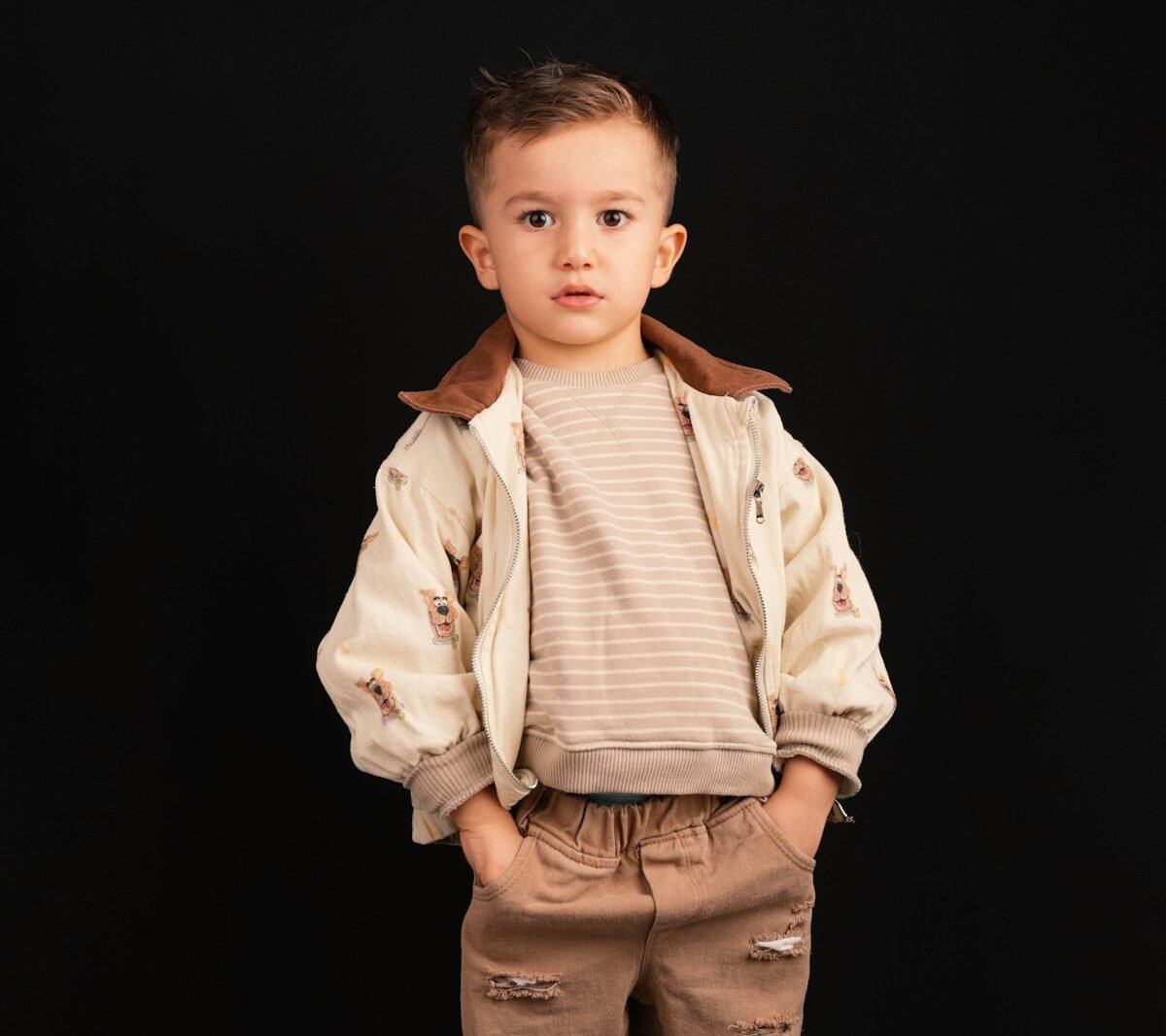 Menino com conjunto de malha bege em fundo preto