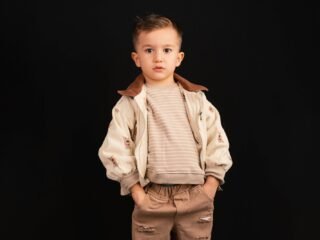 Menino com conjunto de malha bege em fundo preto
