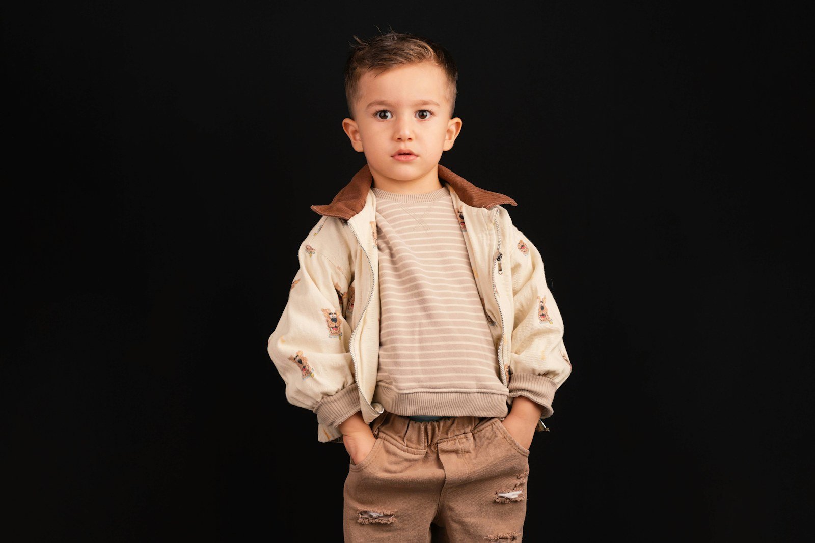 Menino com conjunto de malha bege em fundo preto
