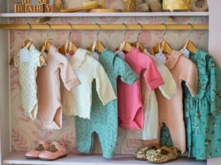 Roupas de bebê em tons pastel penduradas em uma arara