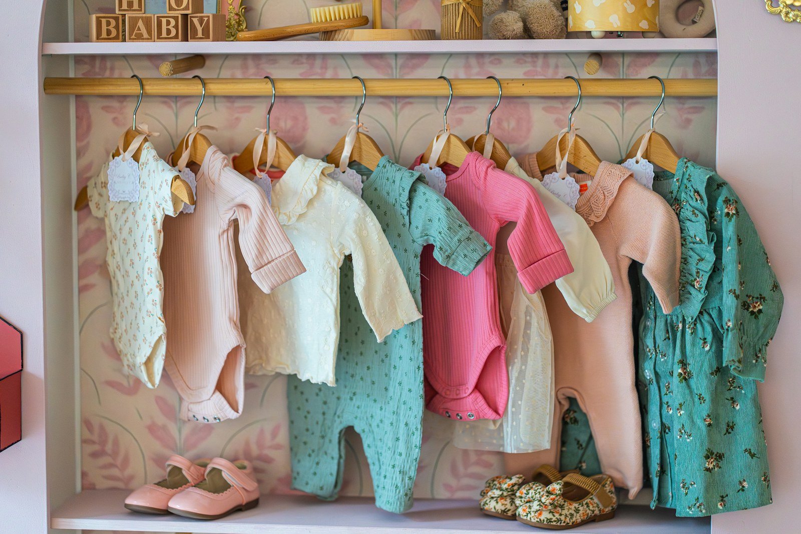 Roupas de bebê em tons pastel penduradas em uma arara